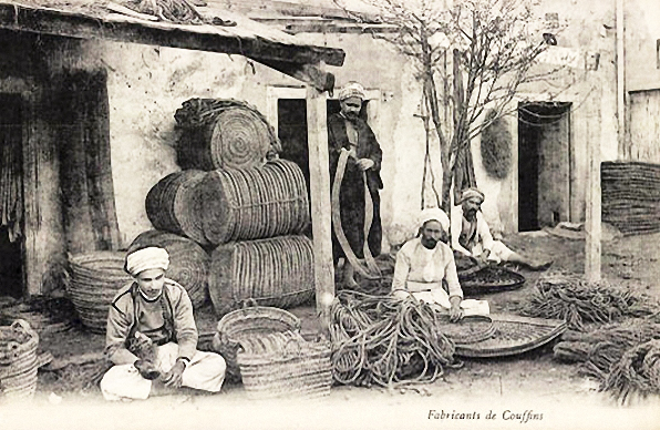 sw-Foto: indischer Korbmacher vor dem Haus sitzend