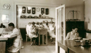 sw-Foto: fünf angestellte Uhrmacher und Goldschmiede sowie eine Sekretärin in der Werkstatt bei der Arbeit