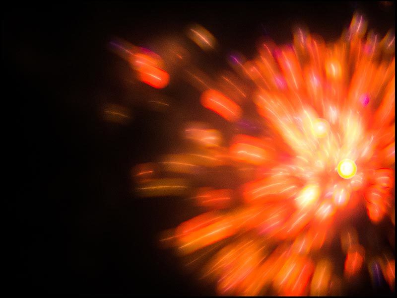 Foto: rötliche Farbexplosion von einem Feuerwerk