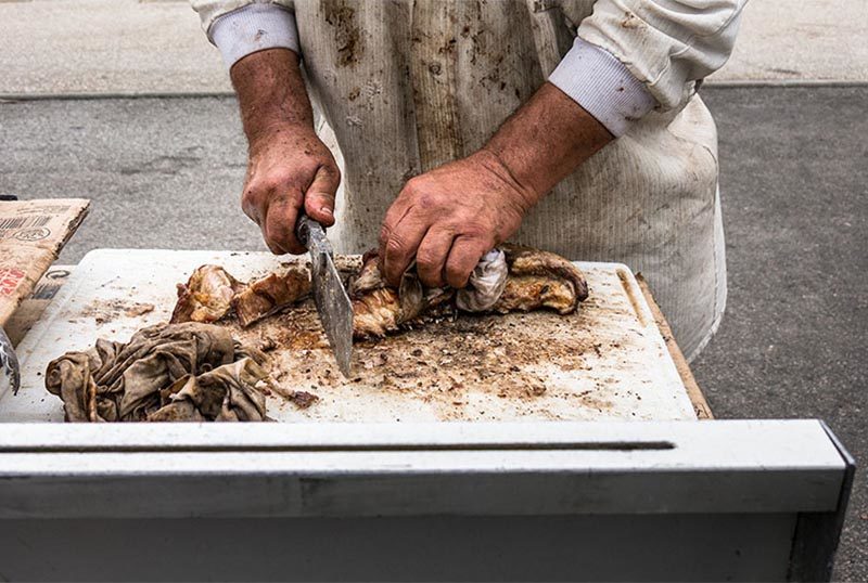 Foto: Metzgerhände zerteilen Lammfleisch mit Hackebeilchen