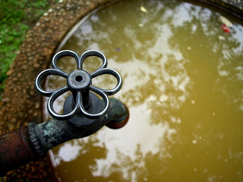 Foto: Draufsicht auf einen mit Wasser gefüllten runden Brunnen mit hübschem Wasserhahn