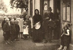 altes sw-Foto: Leierkastenmann umringt von einer barfüßigen Kinderschar