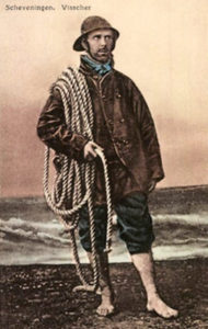 koloriertes Foto: barfüßiger Fischer mit Regenkleidung und Seil steht vor dem Meer