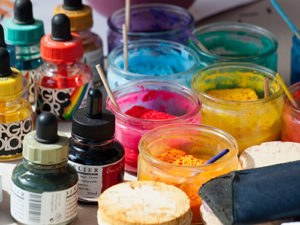 Farbfoto: verschiedene Malfarben in Gläsern und Pipettenflaschen