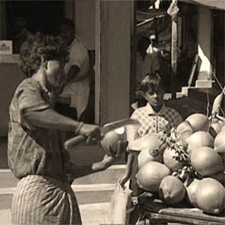 s/w Foto: Kokosverkäufer öffnet ein Kokosnuss mit einer Machete