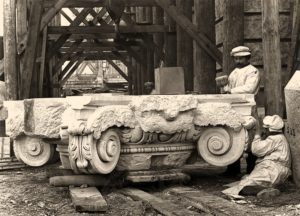 s/w Foto: zwei Steinmetze bei der Bearbeitung eines Säulenkapitells