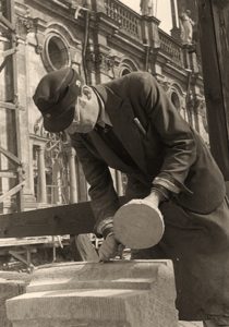 s/w Foto: linkshändiger Steinmetz bearbeitet einen Werkstein mit Meißel und Holzstößel