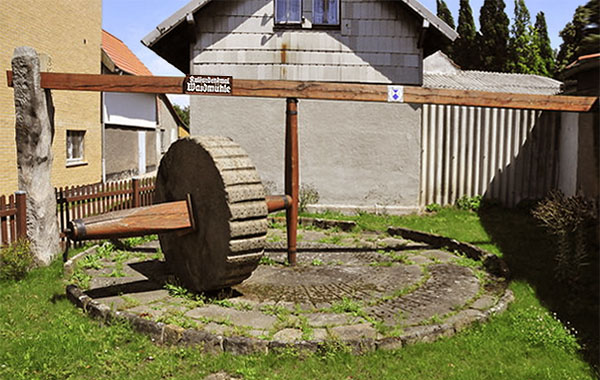 Farbfoto: runder Waidmühlplatz mit Mahlvorrichtung nebst großem runden Mühlstein, der aufrecht benutzt wurde