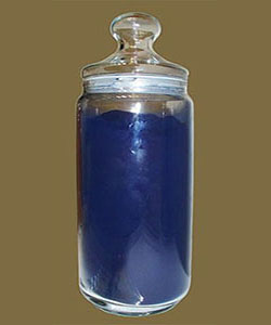Farbfoto: Farbpulver aus Waid in einem Glasbehälter mit Deckel