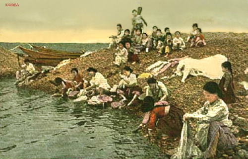 koloriertes Foto: Waschfrauen am Strand und viele Kinder
