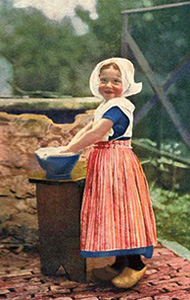 Farbfoto: kleines Mädchen in Holzschuhen mit Waschschüssel neben Brunnen