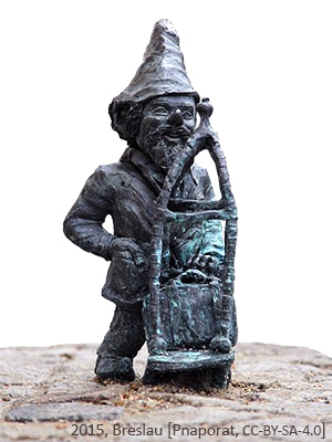 kleine Bronzefigur mit Zipfelmützeund Gepäckkarre
