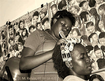 sw Foto: Afrikanische Friseurin dreht Lockenwickler ins Haar einer Kundin - 2016, Tanzania