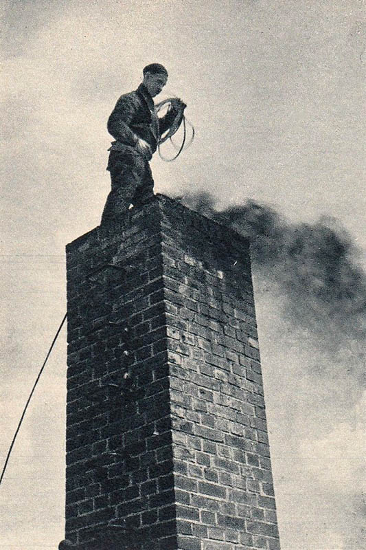 sw-Foto: Kaminfeger steht über dem rußenden Schornstein