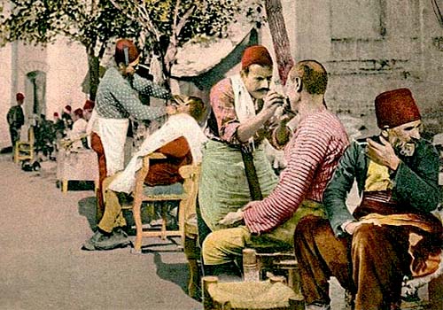 Postkarte: Männer lassen sich am Straßenrand balbieren und frisieren - 1900