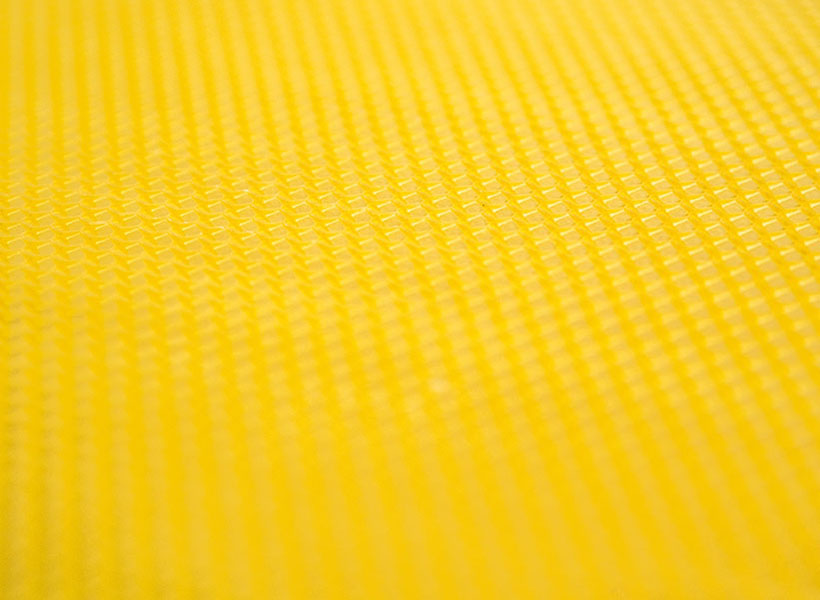 Farbfoto: gelbliche Wachsplatte mit vorgestanztem Wabenmuster
