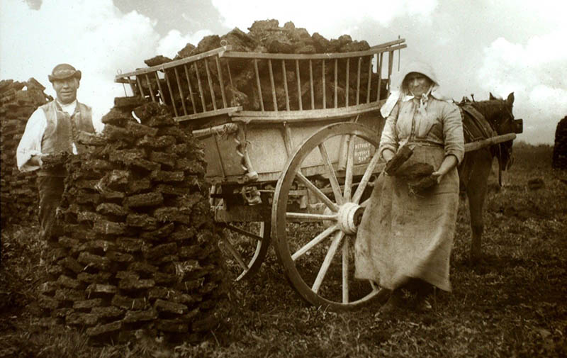 altes Foto: Frau und Mann laden Torfstücke auf einen Pferdekarren