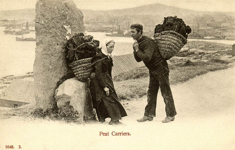 zwei Torfträger mit beladenem Korb auf dem Rücken - Frau und Mann
