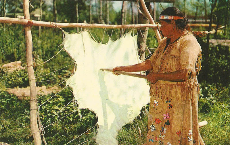AK: Frau in traditioneller Kleidung steht am aufgespannten Leder