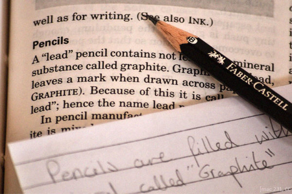 Farbfoto: Bleistift auf Buch und Zettel liegend