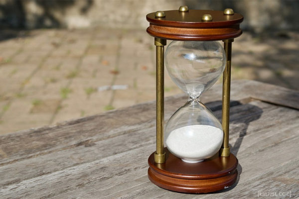 Farbfoto: Stundenglas auf Holzplatte