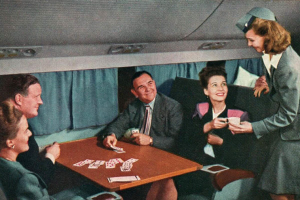 farbige Postkarte: Stewardess bringt kartenspielenden Passagieren Tasse Kaffee