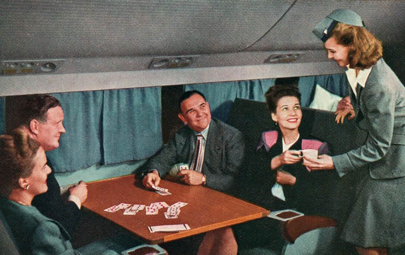 farbige Postkarte: Stewardess bringt kartenspielenden Passagieren Tasse Kaffee