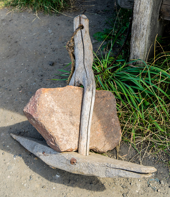 Anker aus Holz mit einem Stein als Gewicht
