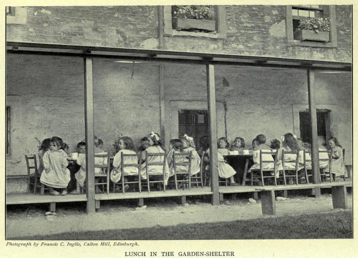 altes Foto: Kinder essen im Freien an Tischen