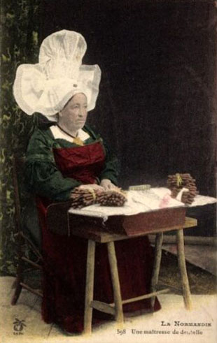 kolorierte Postkarte: Frau mit großer Haube klöppelt Spitze
